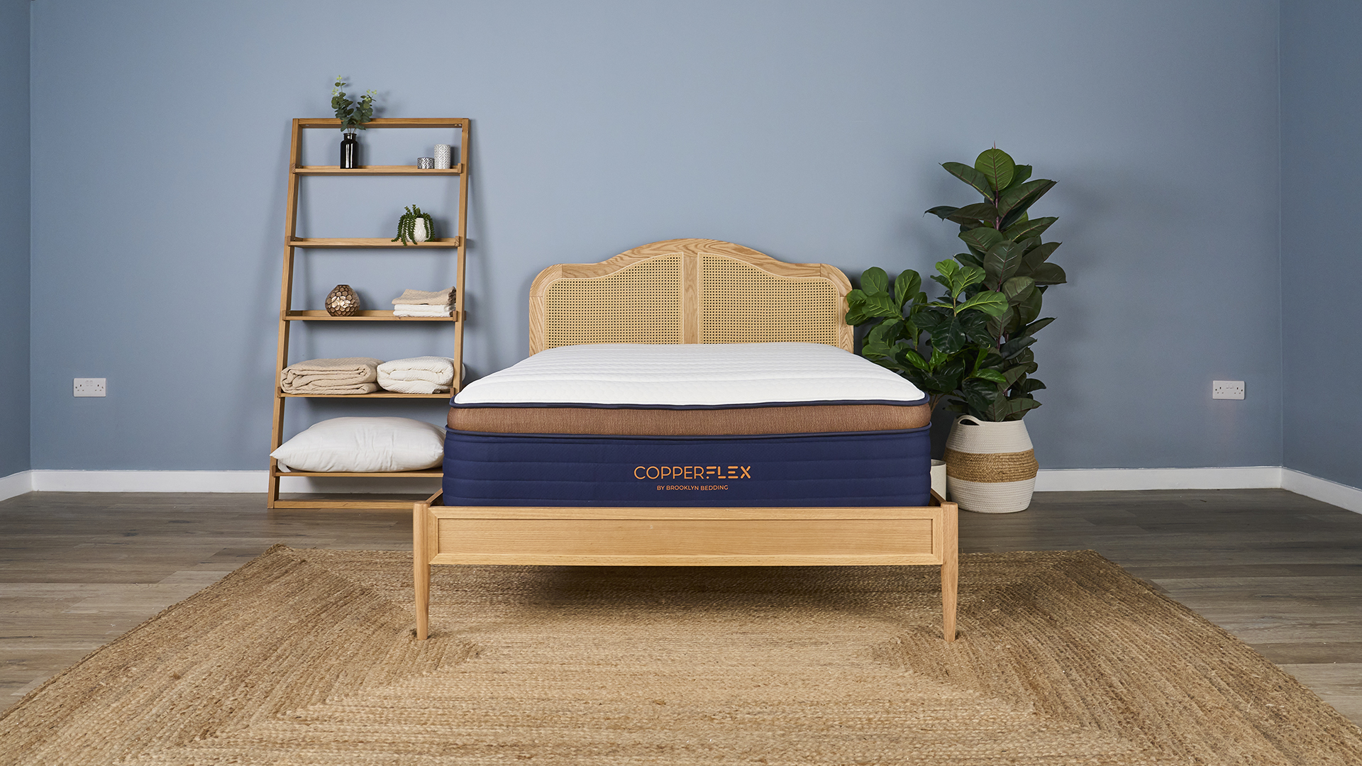Λευκό, ναυτικό και χάλκινο Brooklyn Bedding Copperflex Pro Hybrid Mattress στο Bedframe Rattan στο Tom's Guide Sleep Studio με ράφια και φυτά